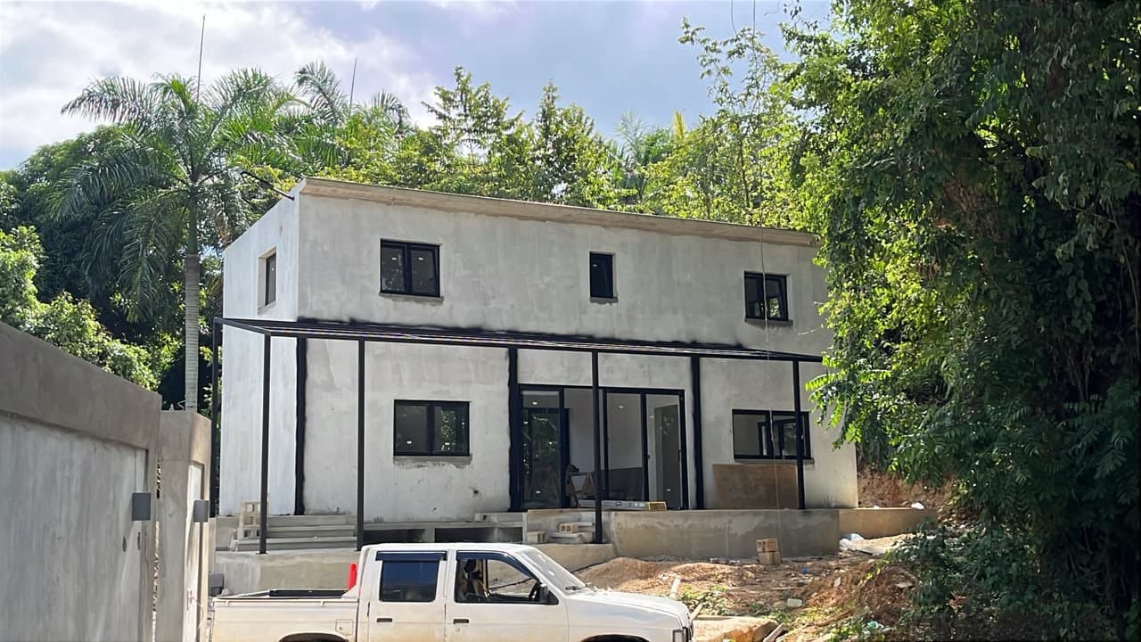 The near-finished Samanea loft seen from the front, white render, full-width covered terrace and glazing complete